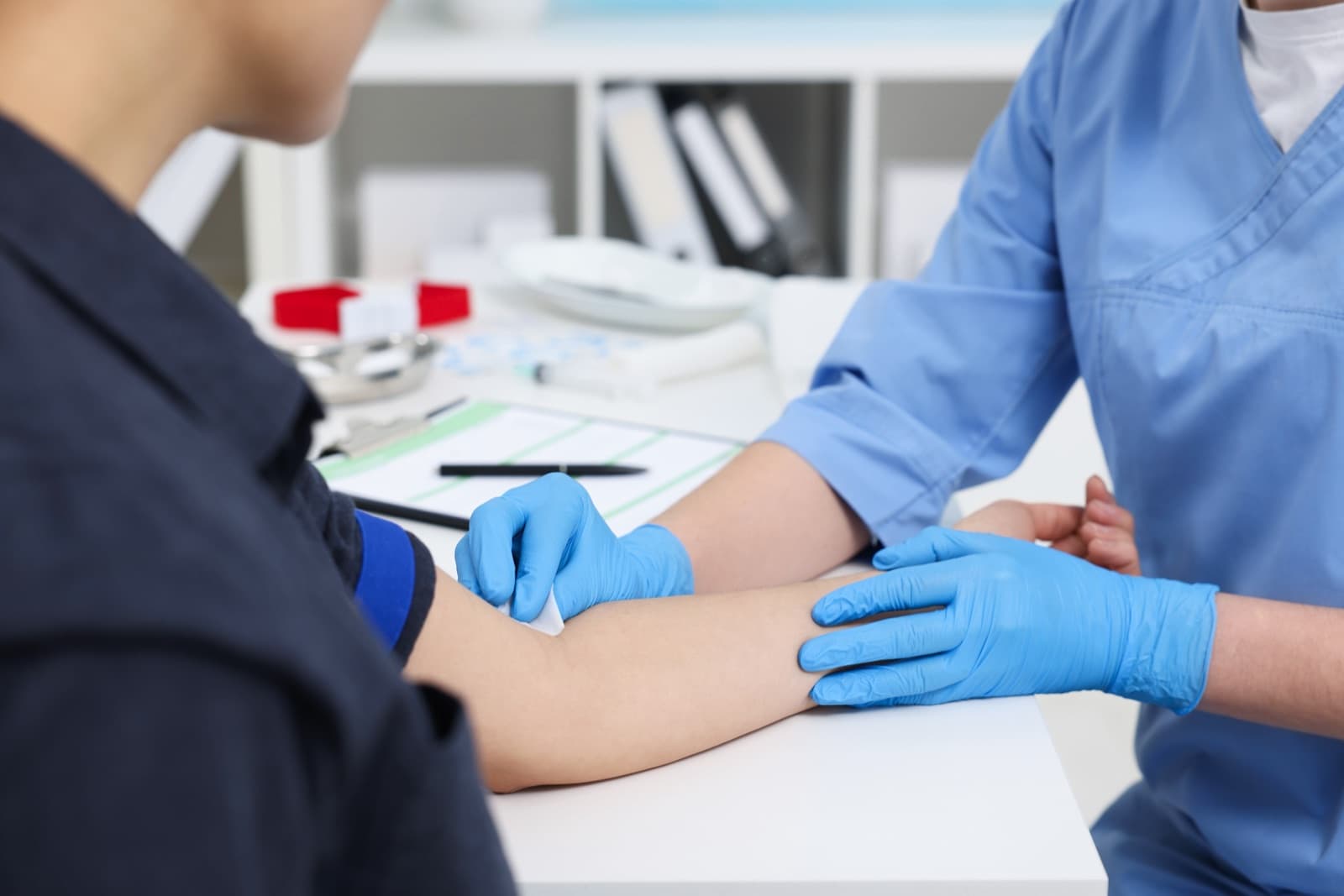 A patient having an in-person blood draw performed by a lab technician